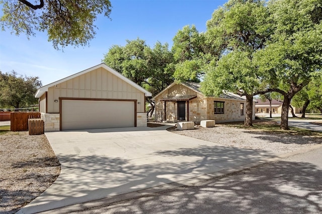 ranch-style house with concrete driveway, stone siding, board and batten siding, and fence