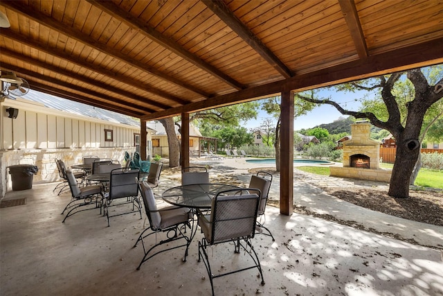 view of patio with an outdoor stone fireplace, an outdoor pool, and outdoor dining area
