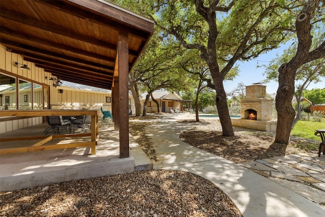 exterior space featuring an outdoor pool, an outdoor stone fireplace, and a patio area