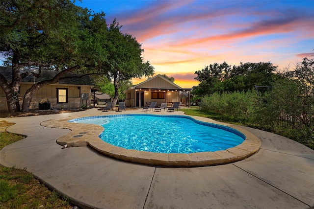 pool at dusk featuring a patio and an outdoor pool