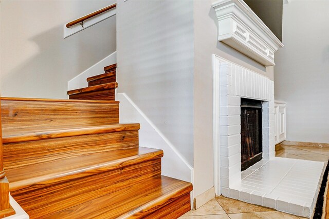 939 Legend Spring Dr, Katy, TX 77494 - stairs featuring baseboards, a brick fireplace, and tile patterned floors
