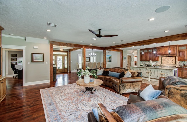 living area featuring dark wood-style flooring, a textured ceiling, ceiling fan with notable chandelier, baseboards, and visible vents