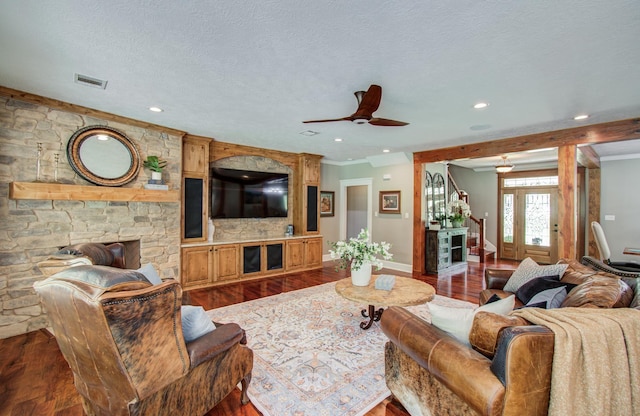 living area featuring a stone fireplace, a ceiling fan, recessed lighting, wood finished floors, and visible vents