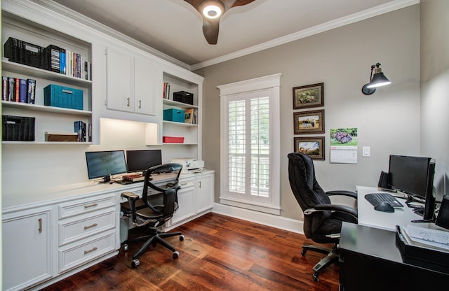 office area with dark wood-style flooring, built in desk, a ceiling fan, baseboards, and ornamental molding