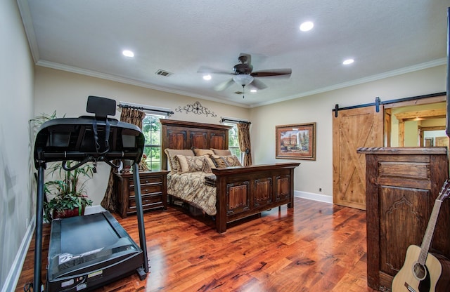 bedroom with visible vents, wood finished floors, baseboards, recessed lighting, and a barn door