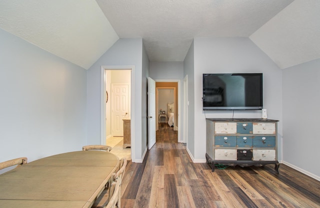bedroom featuring baseboards, ensuite bathroom, vaulted ceiling, and dark wood finished floors