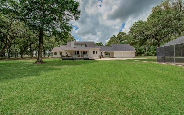 rear view of house featuring a garage, a wooden deck, and a lawn