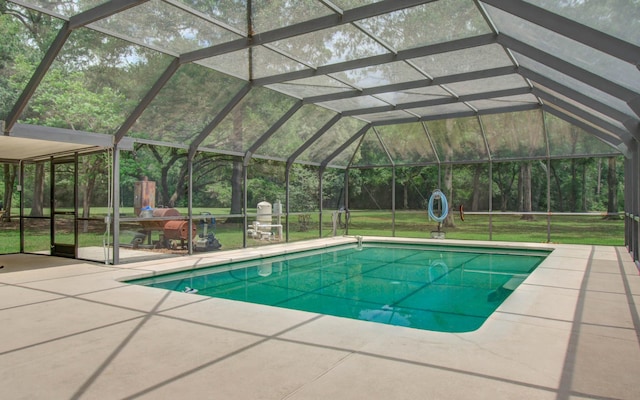 outdoor pool with a lawn, a patio area, and a lanai