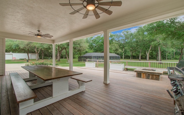 wooden terrace with a yard, an outbuilding, a ceiling fan, and an outdoor fire pit