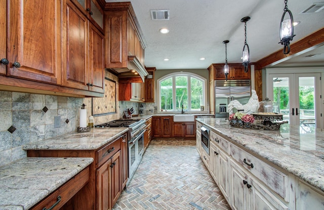kitchen featuring visible vents, a sink, built in appliances, and brown cabinets