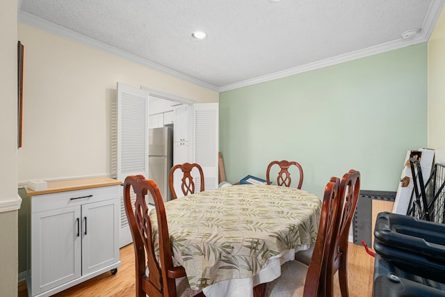 dining space with a textured ceiling, crown molding, and light wood-style flooring