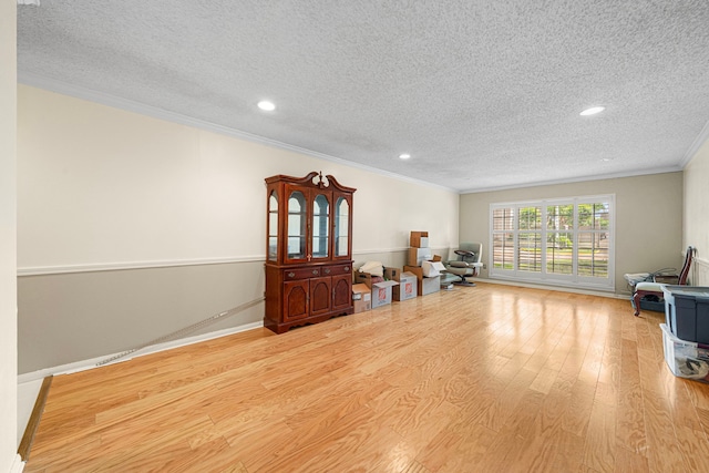 interior space with a textured ceiling, baseboards, recessed lighting, ornamental molding, and wood finished floors