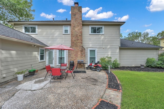 rear view of property featuring roof with shingles, outdoor dining area, a chimney, a patio, and a yard