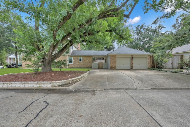single story home with an attached garage, fence, brick siding, and concrete driveway