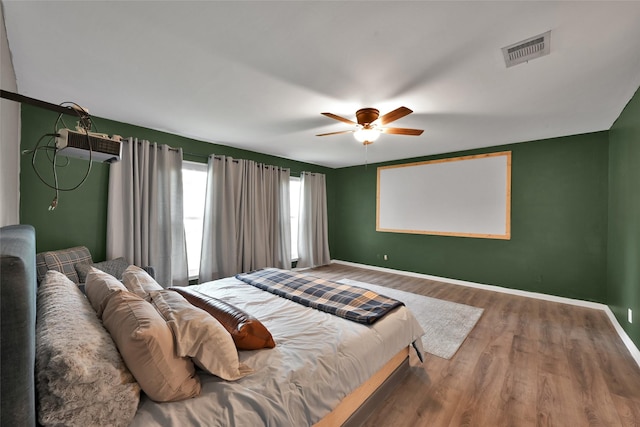 bedroom featuring baseboards, ceiling fan, wood finished floors, and visible vents