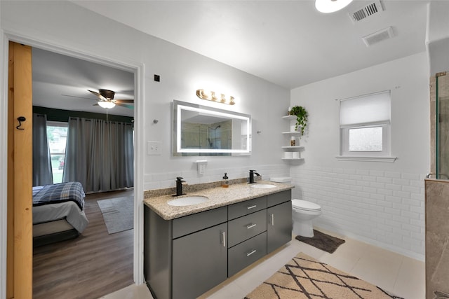 full bath featuring double vanity, visible vents, a sink, and a wainscoted wall