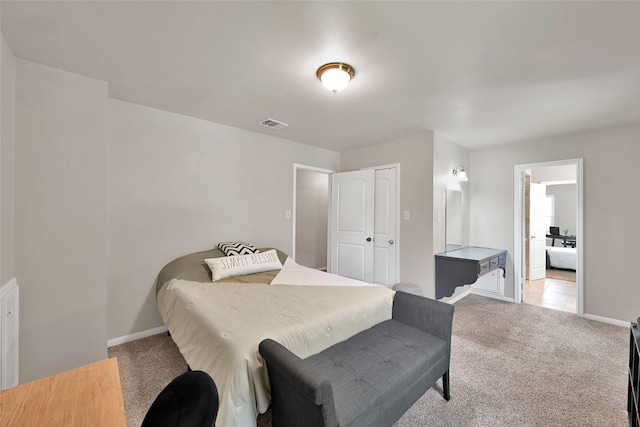 bedroom featuring light colored carpet, ensuite bath, baseboards, visible vents, and a closet