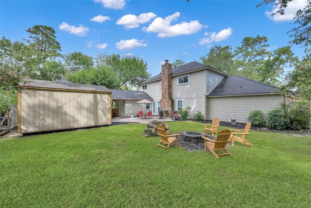 back of house with a patio, a fire pit, a yard, and a chimney