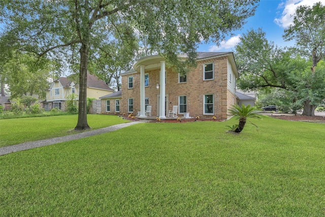 greek revival inspired property featuring brick siding and a front yard