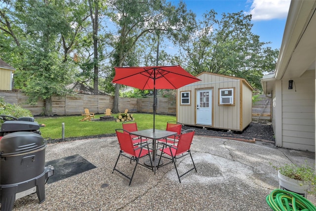 view of patio / terrace featuring a grill, outdoor dining area, a fenced backyard, a storage shed, and an outbuilding