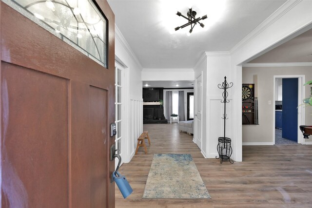 entrance foyer with crown molding, baseboards, a chandelier, and wood finished floors