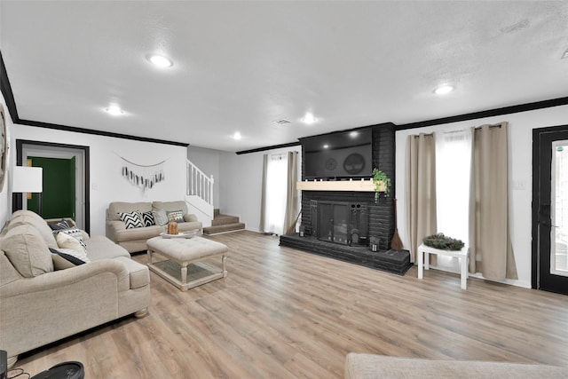 living area with stairs, ornamental molding, a brick fireplace, and wood finished floors