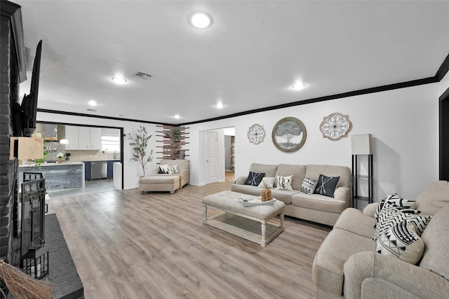 living area with crown molding, recessed lighting, visible vents, and light wood-type flooring