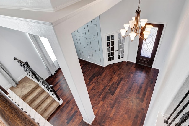 entryway with ornamental molding, wood finished floors, and a notable chandelier