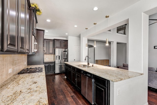 kitchen featuring a sink, stainless steel appliances, dark wood-style floors, light stone countertops, and backsplash