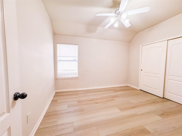 unfurnished bedroom featuring a ceiling fan, baseboards, vaulted ceiling, and light wood-type flooring