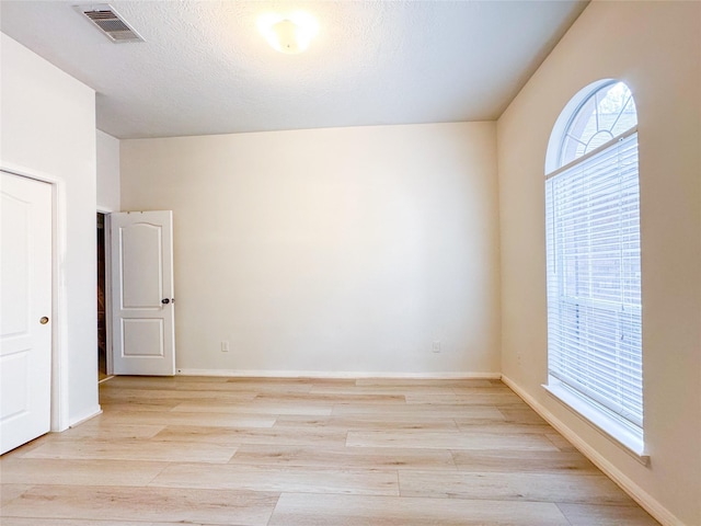 spare room with visible vents, light wood-style flooring, and baseboards