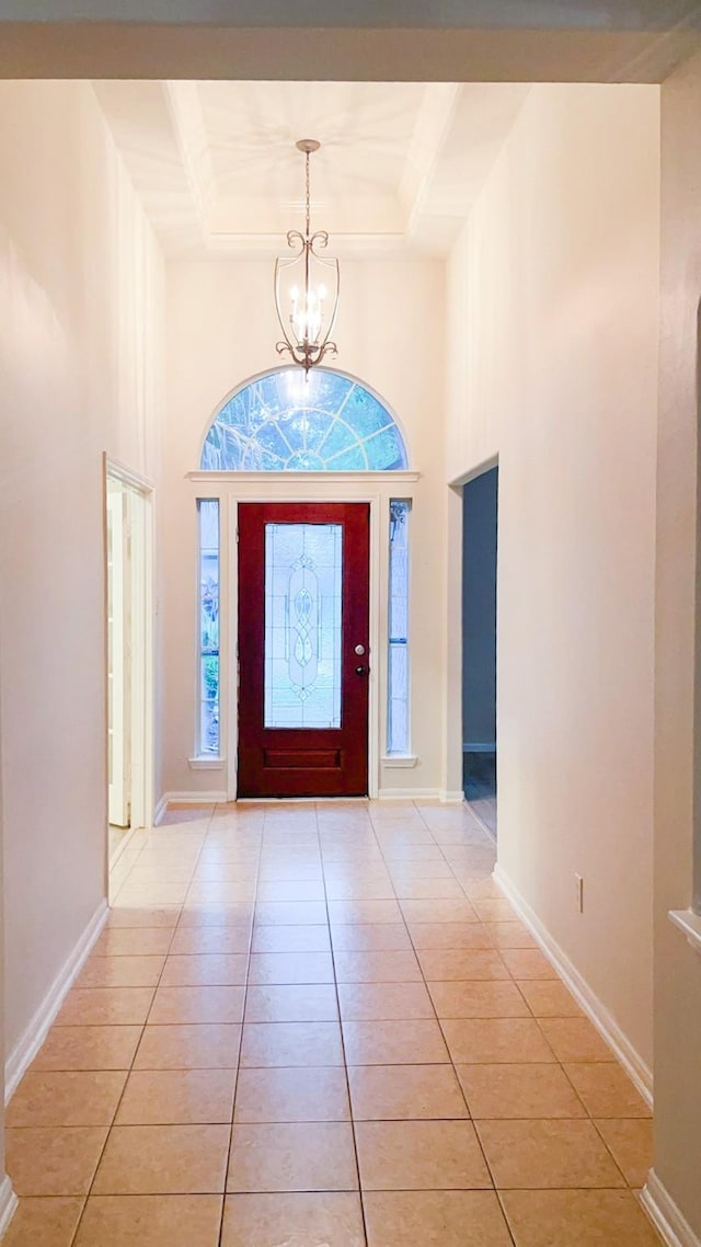 foyer featuring an inviting chandelier, light tile patterned floors, baseboards, and a high ceiling
