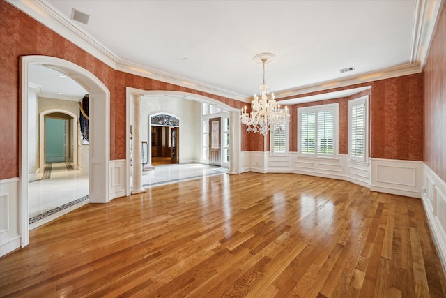 2 Wexford Ct, Piney Point Village, TX 77024 - unfurnished dining area featuring ornamental molding, arched walkways, a chandelier, a wainscoted wall, and light wood-type flooring