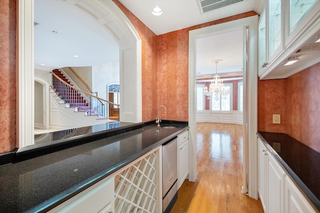2 Wexford Ct, Piney Point Village, TX 77024 - bar area with a sink, light wood-style flooring, a chandelier, arched walkways, and stairs