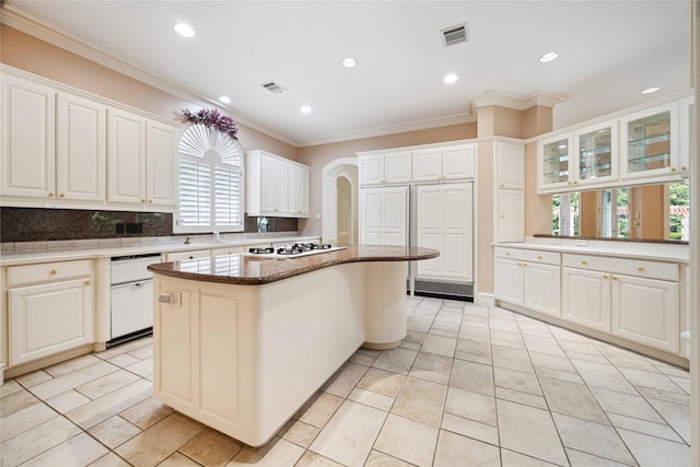 kitchen featuring arched walkways, white appliances, a kitchen island, visible vents, and crown molding