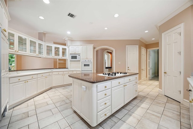 2 Wexford Ct, Piney Point Village, TX 77024 - kitchen with white appliances, a center island, arched walkways, glass insert cabinets, and white cabinets