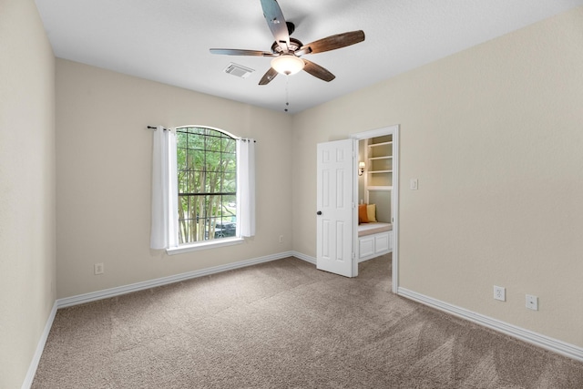 empty room with baseboards, ceiling fan, carpet flooring, and visible vents