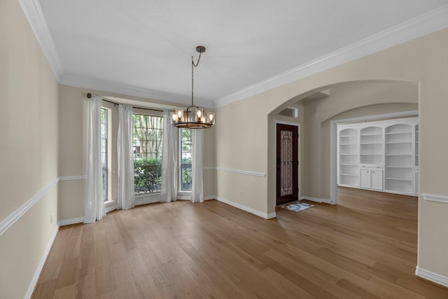unfurnished dining area with arched walkways, baseboards, visible vents, and a notable chandelier