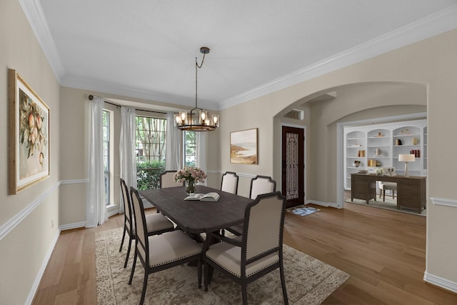 dining area with light wood finished floors, arched walkways, a chandelier, visible vents, and ornamental molding