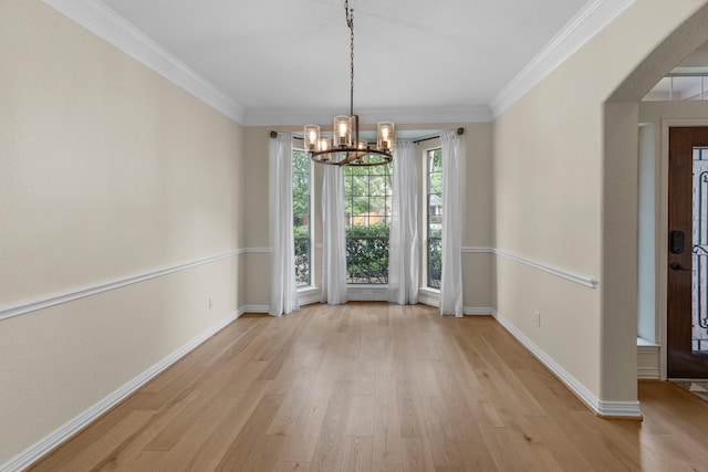 unfurnished dining area with an inviting chandelier, baseboards, crown molding, and light wood-type flooring
