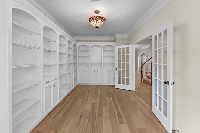 interior space featuring arched walkways, ornamental molding, french doors, and light wood finished floors
