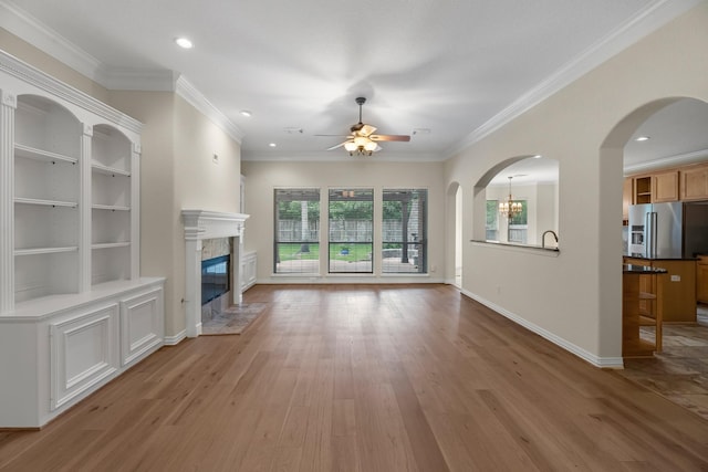 unfurnished living room with crown molding, a fireplace, recessed lighting, light wood finished floors, and ceiling fan with notable chandelier