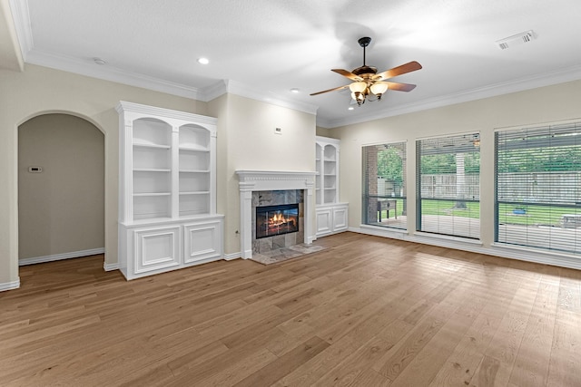 unfurnished living room with ceiling fan, visible vents, arched walkways, a fireplace, and wood finished floors
