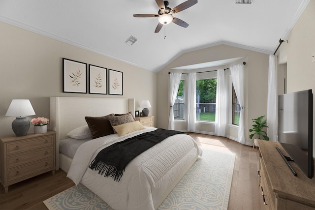 bedroom featuring visible vents, light wood finished floors, crown molding, and vaulted ceiling