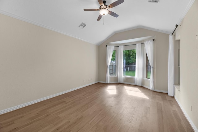 spare room with light wood-style floors, a ceiling fan, vaulted ceiling, visible vents, and ornamental molding