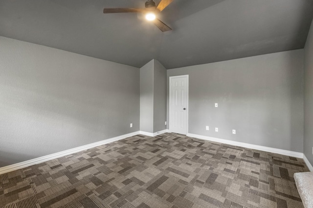 carpeted empty room with ceiling fan, vaulted ceiling, and baseboards