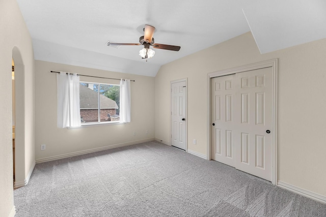 unfurnished bedroom with carpet flooring, arched walkways, and baseboards