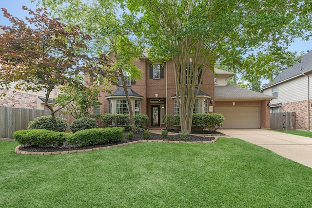 view of front of home with brick siding, fence, a front yard, and concrete driveway