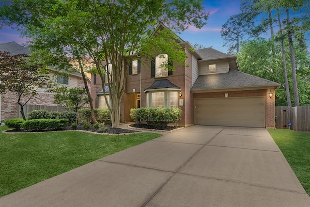 traditional-style home featuring fence, a yard, a shingled roof, and concrete driveway