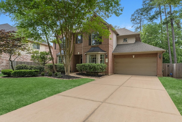 traditional-style home with fence, roof with shingles, concrete driveway, and a front lawn